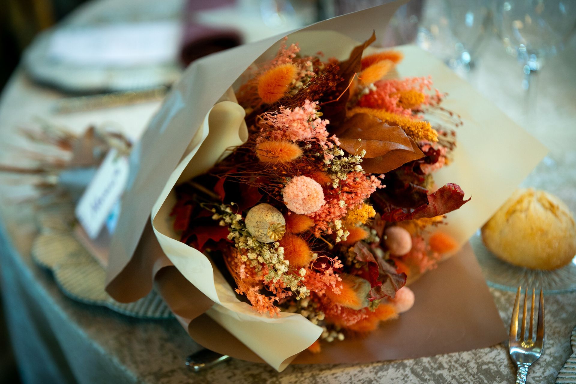 Bouquet décoratif de fleurs et de baies aux couleurs d'automne, emballé dans du papier sur une table à manger