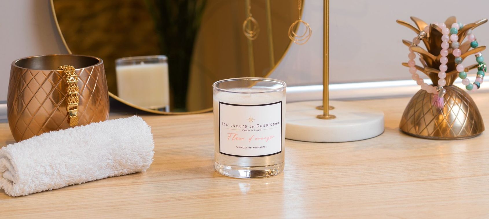 Table de style spa avec une serviette blanche, une bougie allumée et des éléments décoratifs en cuivre sur une surface en bois