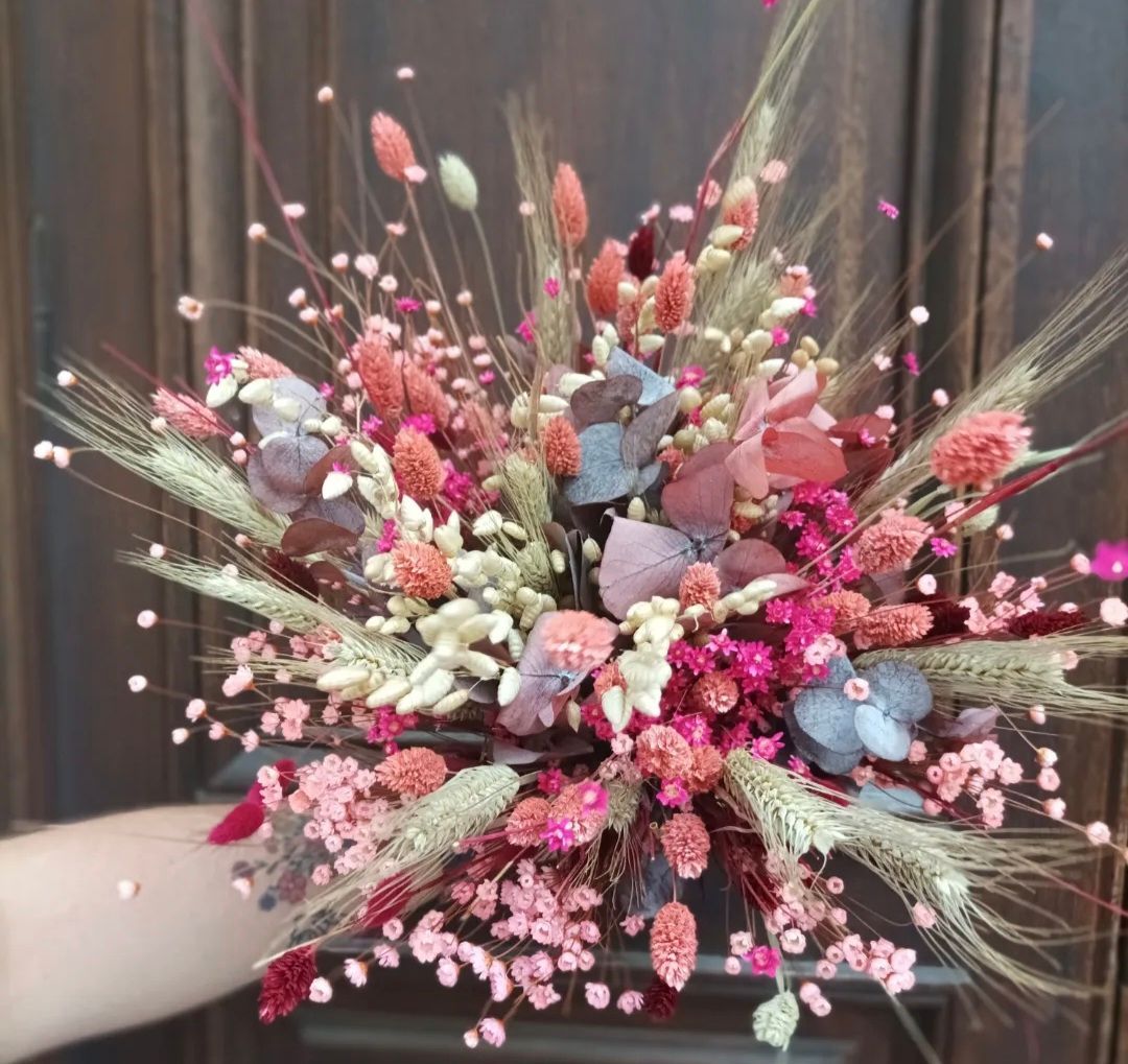 Bouquet de fleurs séchées roses, bleues et blanches avec des graminées dans un vase