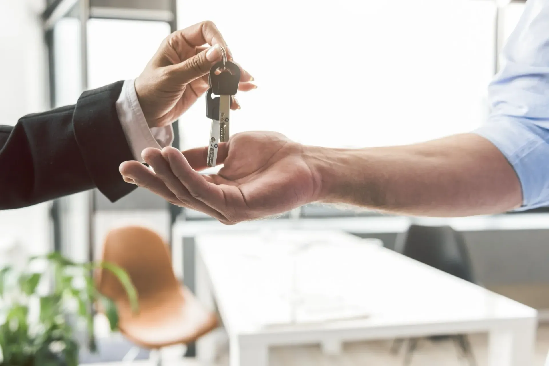 Persona entregando llaves a otra persona. En el interior.