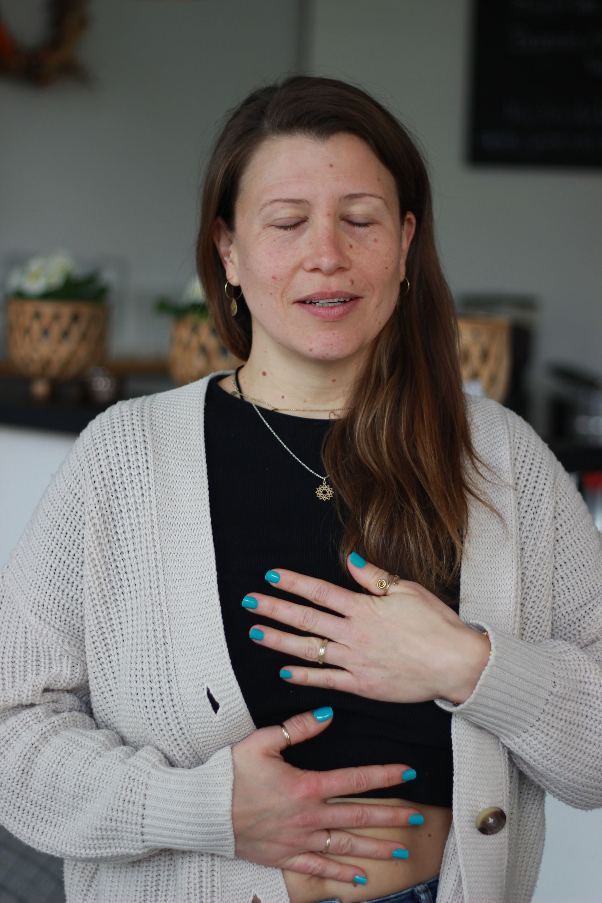 Eine Frau in einem Pullover hält ihre Brust mit den Händen.