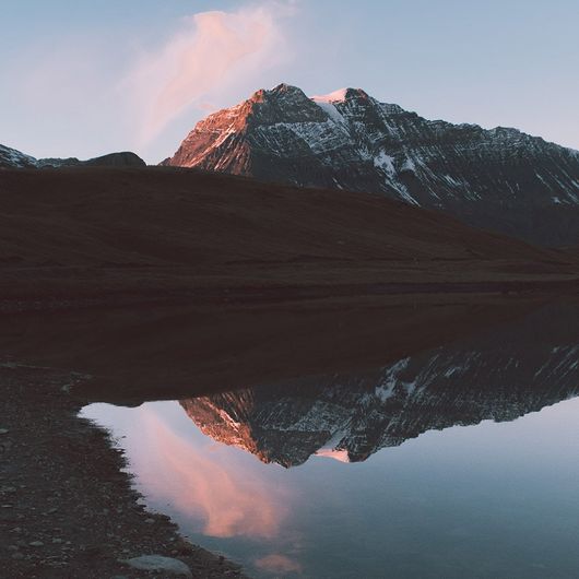 Ein Bergsee spiegelt die Berge und den Himmel wieder.