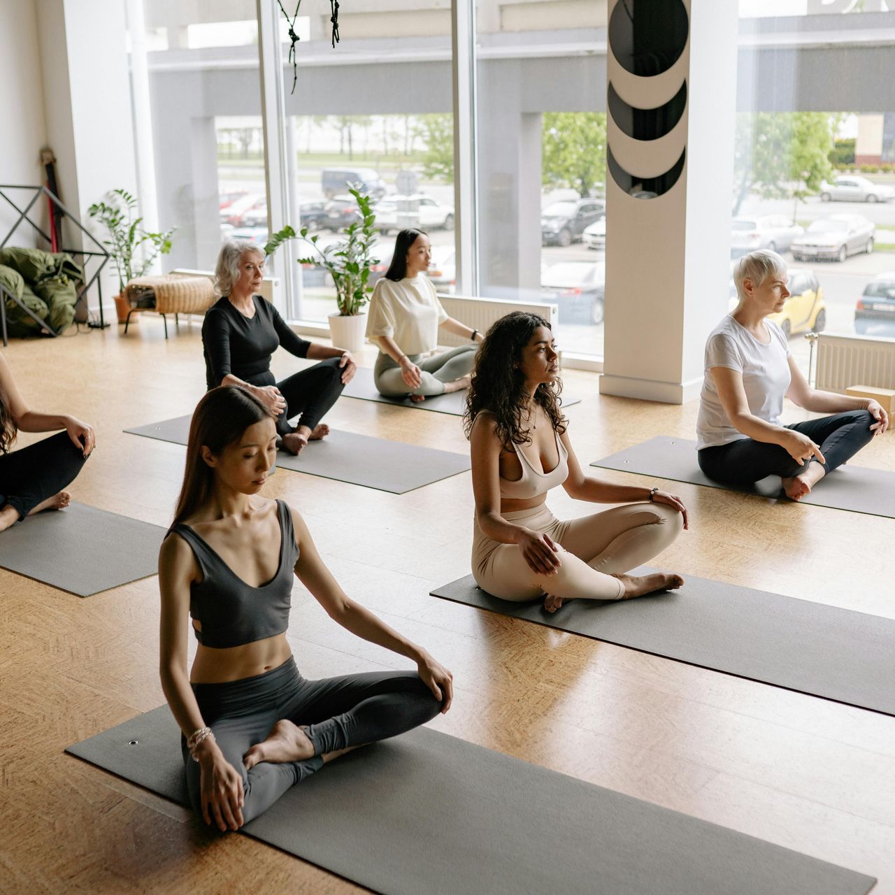 Eine Gruppe von Menschen sitzt in einem Raum auf Yogamatten.