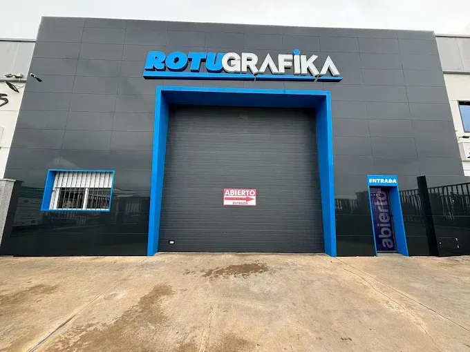 Exterior de un edificio para ROTUGRAFIKA, con una paleta de colores azul y gris. Una gran puerta de garaje está centrada y un cartel dice 