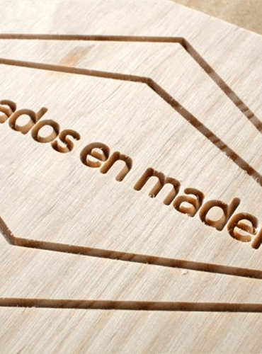 Primer plano de una superficie de madera con texto tallado: