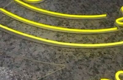 Hebras de luz de neón amarillas sobre una superficie con textura oscura, iluminando parcialmente.