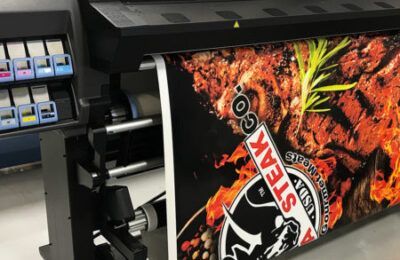 Impresora de gran formato que produce una pancarta publicitaria de alimentos.
