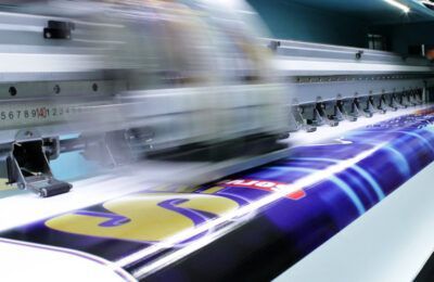 Impresora de gran formato imprimiendo una pancarta colorida.