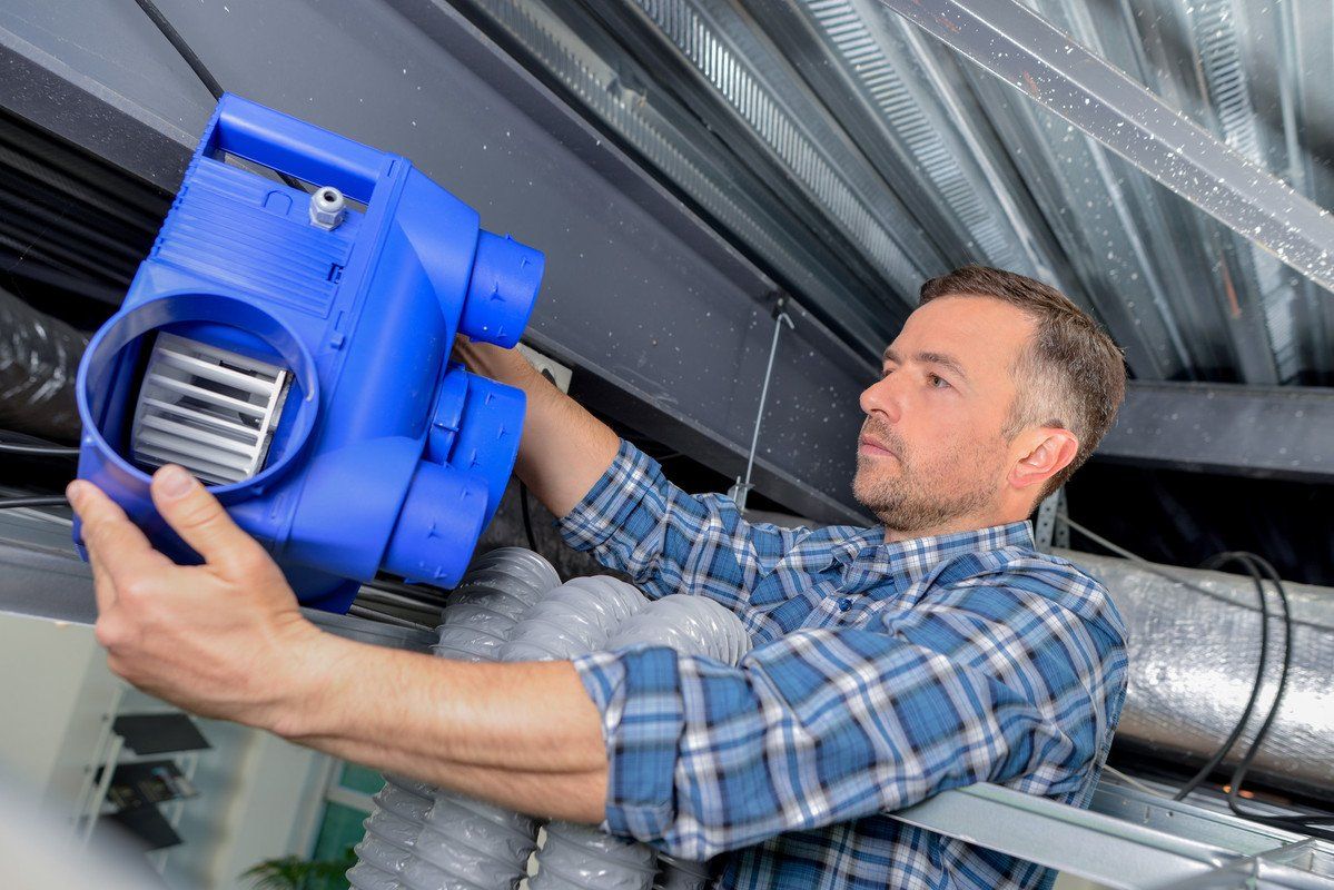 Technicien qui installe une VMC dans les combles d'une maison