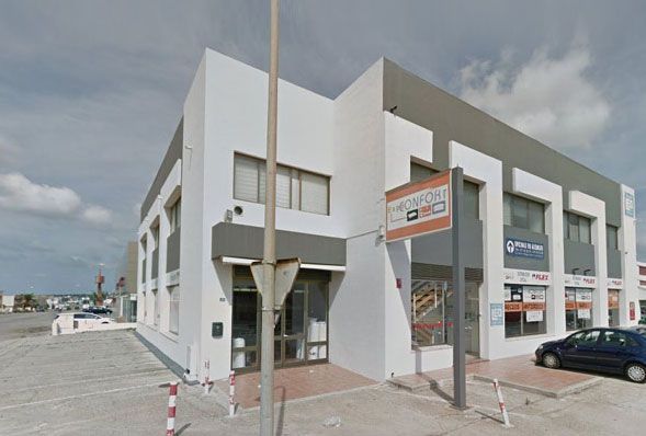 Un edificio blanco con un coche aparcado delante.