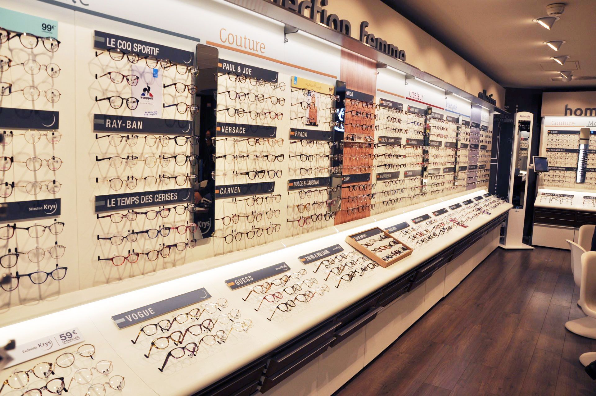 Des montures de lunettes exposées sur un mur et des étagères dans le magasin d'Optique Pellé Krys.
