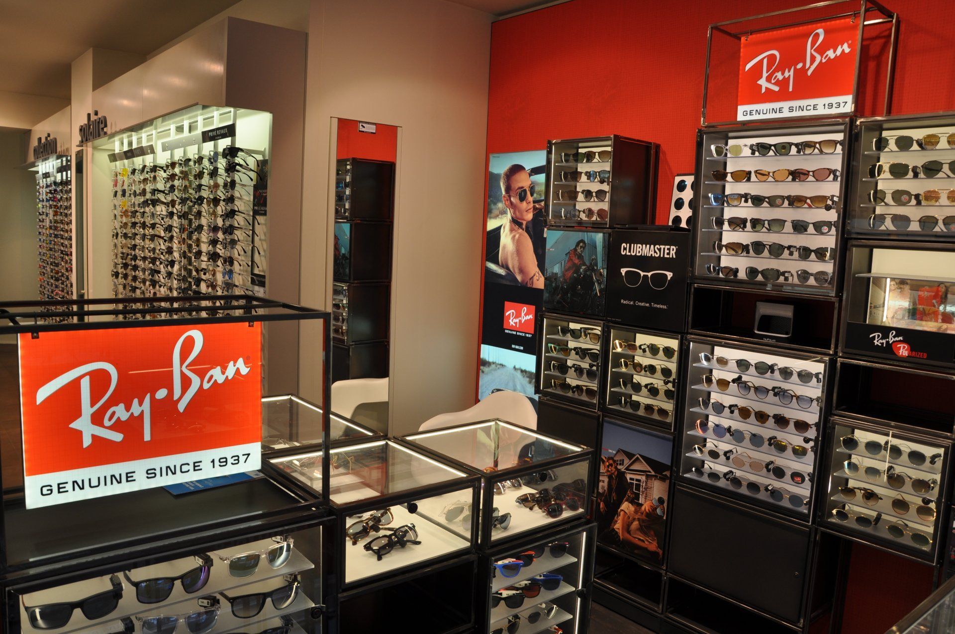 Présentoir de lunettes de soleil Ray-Ban dans un magasin, avec le logo rouge et blanc.