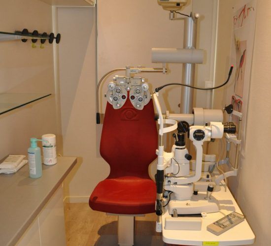 Fauteuil d'examen rouge, équipement optique dans un cabinet médical pour les examens de la vue.