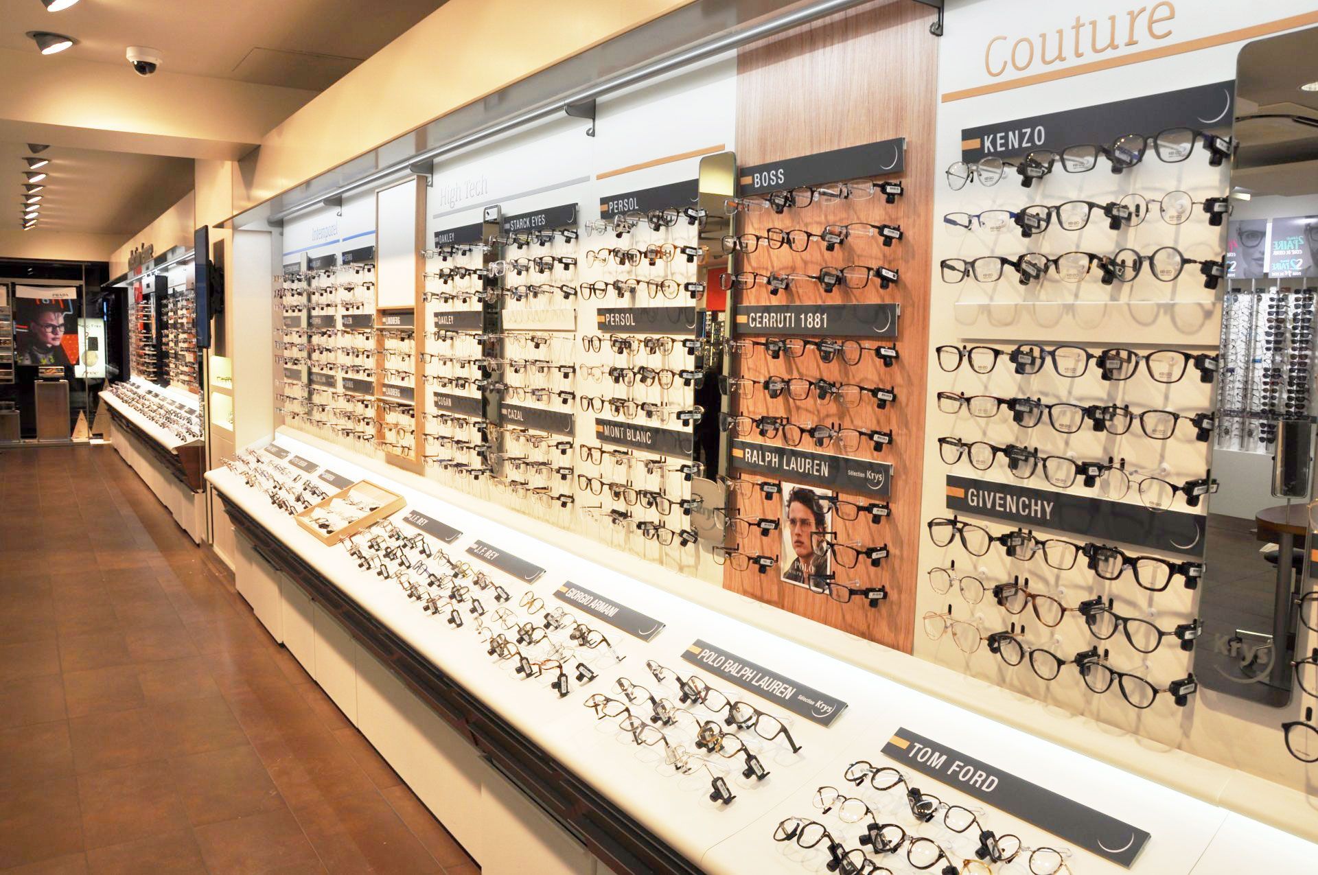 Intérieur du magasin d'Optique Pellé Krys ; présentation de nombreuses paires de lunettes sur les étagères et les murs.