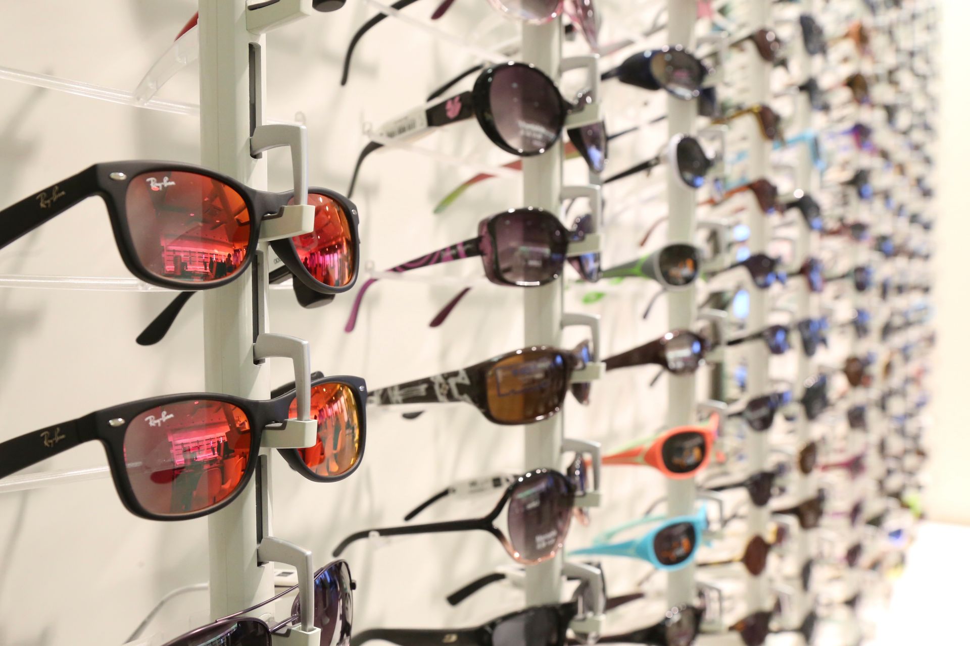 Lunettes de soleil exposées sur le mur d'un magasin, différents styles et couleurs sont visibles.