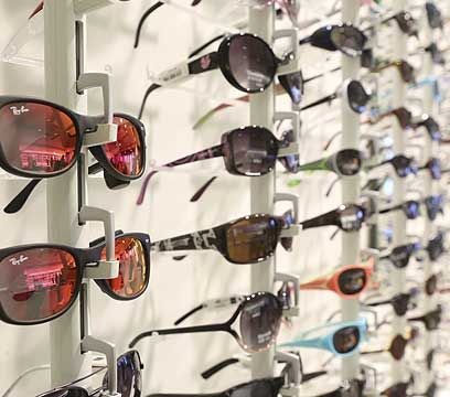 Lunettes de soleil présentées sur un présentoir dans un magasin, différents styles et couleurs sont visibles.