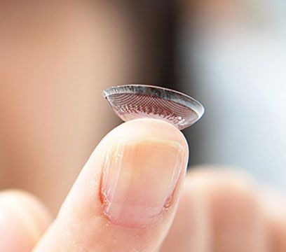 Lentille de contact tenue sur le bout du doigt, laissant apparaître les détails nervurés.