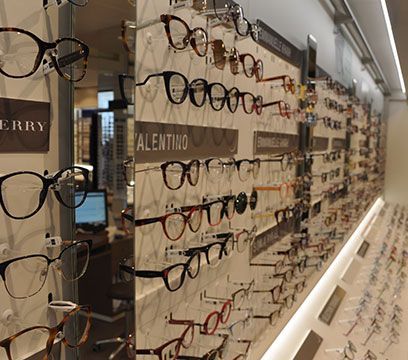 Lunettes exposées sur un mur à l'intérieur d'un magasin d'optique ; montures de styles et de couleurs variés.
