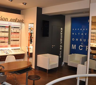 Intérieur d'un cabinet d'opticien ; salle d'attente avec chaises et tableau optométrique.