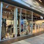 Façade avec de grandes vitrines exposant des lunettes et des articles de décoration. Intérieur lumineux avec des clients.