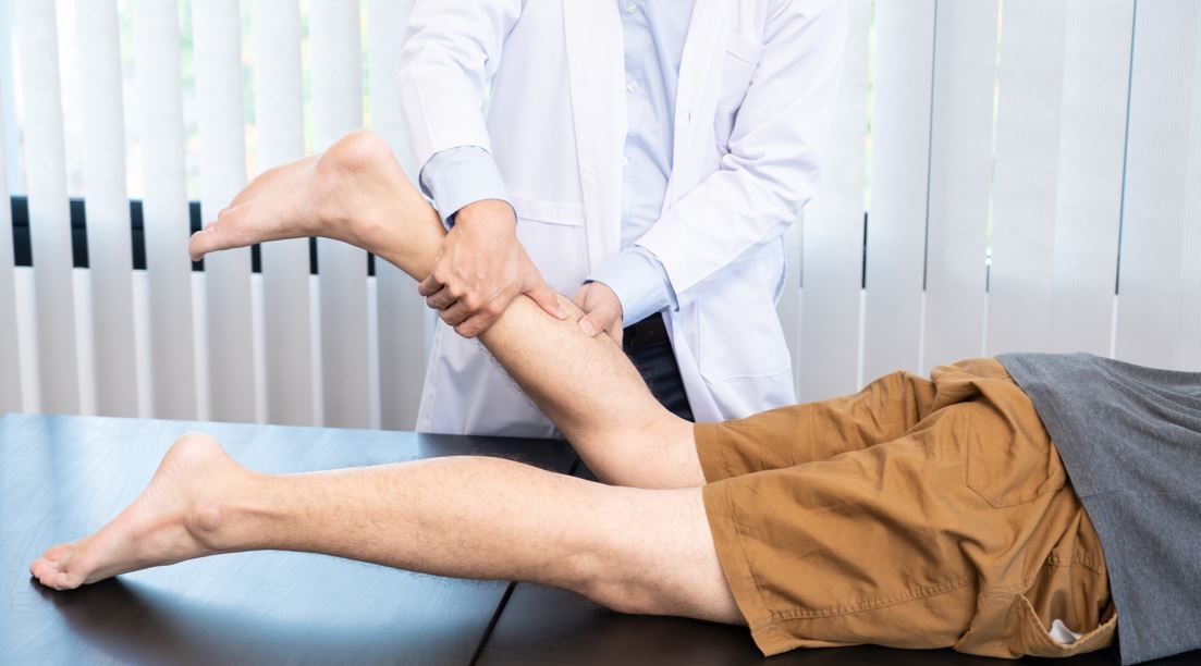 Un médico examina la pierna de un paciente.