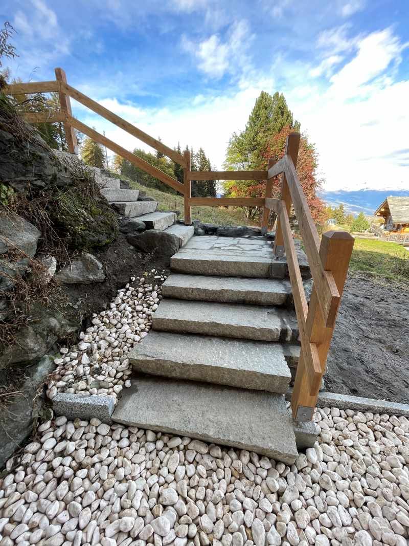 Un ensemble d'escaliers en pierre avec une rampe en bois et une clôture en bois.