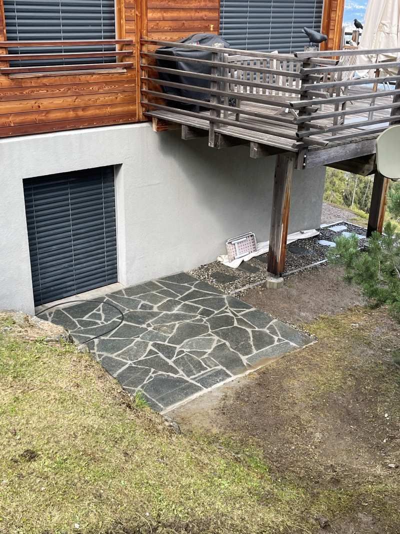 Une allée en pierre menant à une terrasse en bois à côté d'une maison.