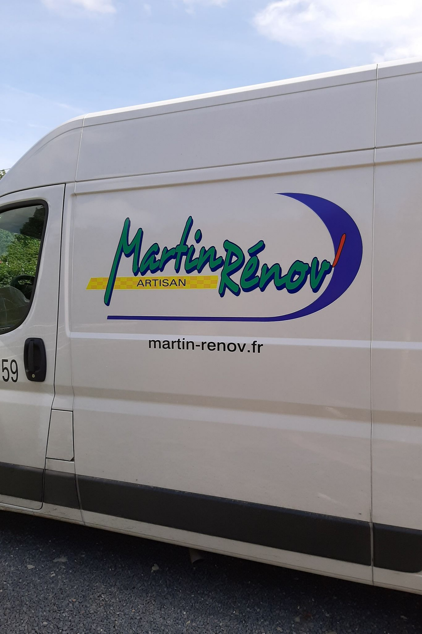 Fourgonnette blanche avec le logo de Martin Rénov' en vert, jaune et bleu.