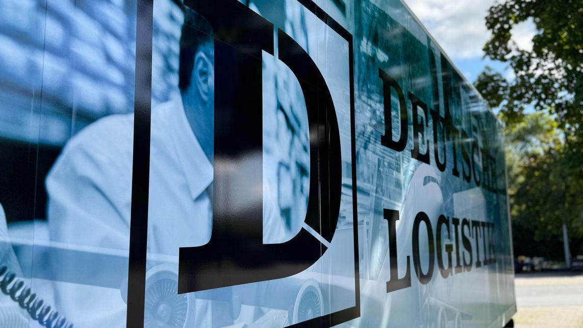 Seite eines Lieferwagens der Deutschen Logistics mit einem großen schwarzen „D“ über einem blau getönten Arbeiterbild und Logo.