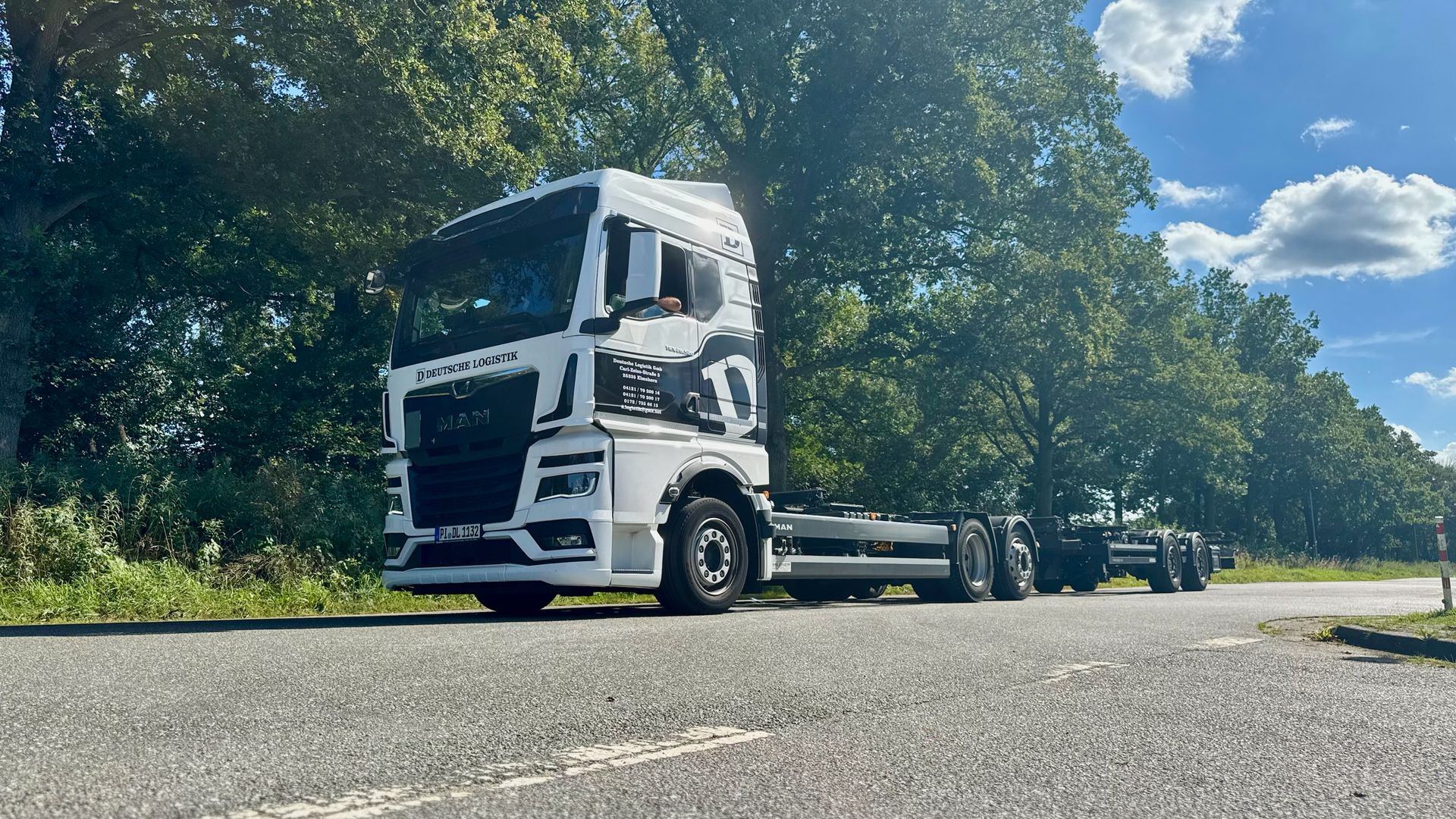 Weiße Lastwagen mit schwarzen Mustern parken an einem sonnigen Tag auf einem Parkplatz.