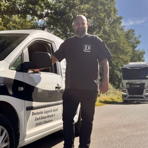 Mann steht neben einem weißen Lieferwagen mit Logo, im Hintergrund ein LKW. Sonniger Tag, draußen.