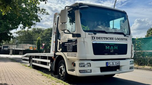 Weißer MAN-Abschleppwagen mit der Aufschrift „Deutsche Logistik“ auf einer Straße geparkt.