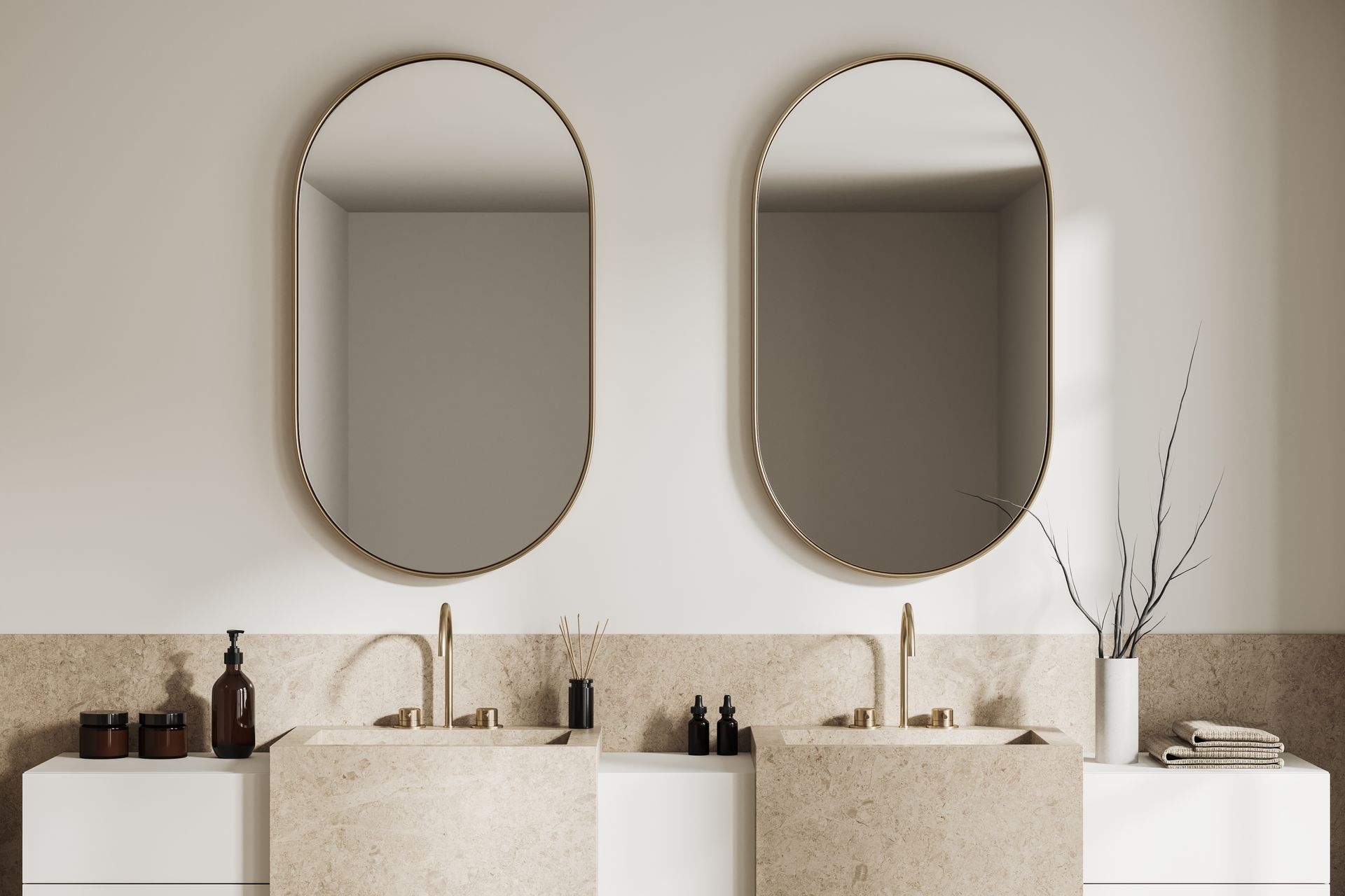 Salle de bains avec deux miroirs ovales, lavabos en pierre et robinetterie dorée.