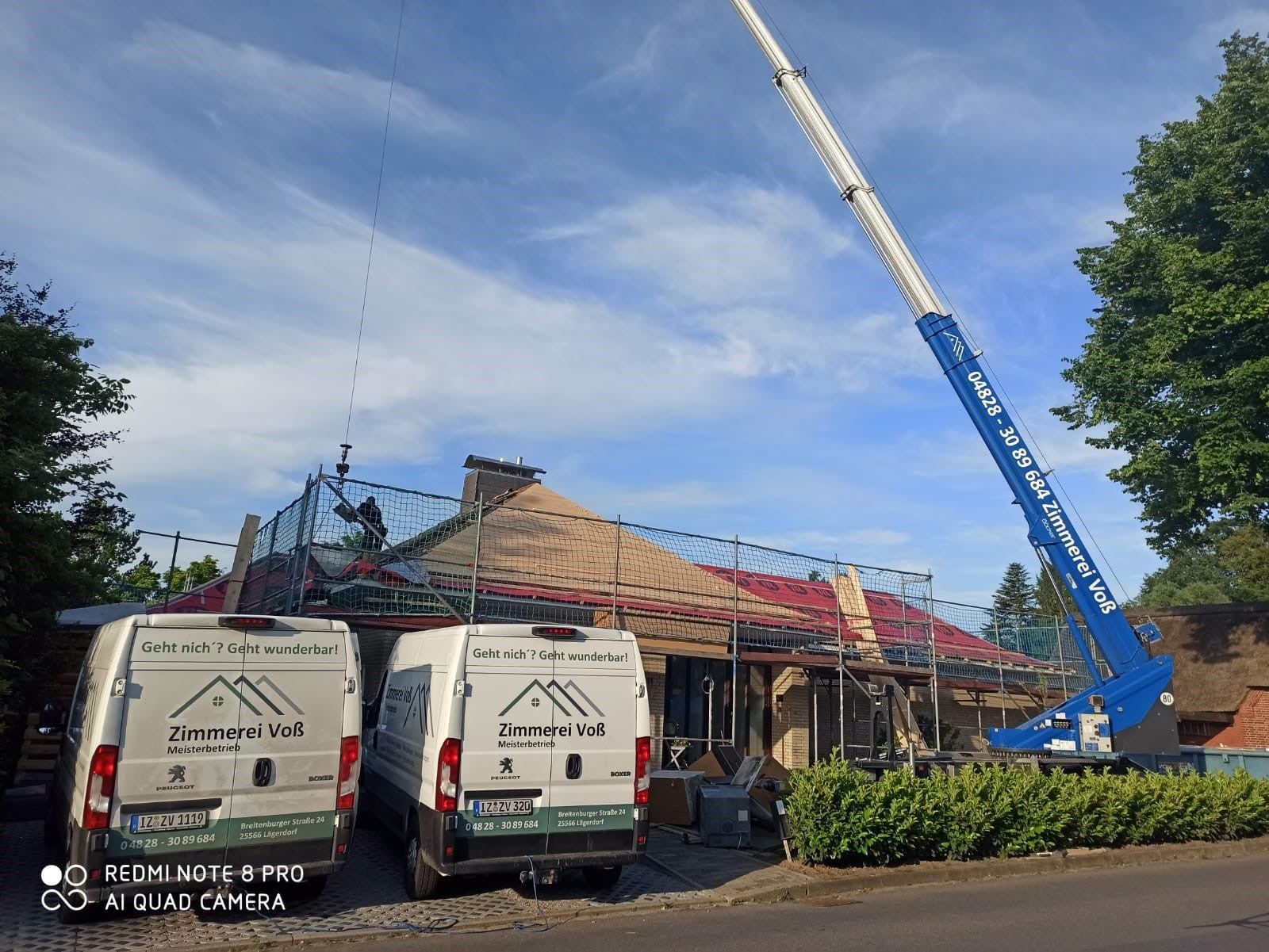 Zwei Lieferwagen stehen vor einem im Bau befindlichen Gebäude.