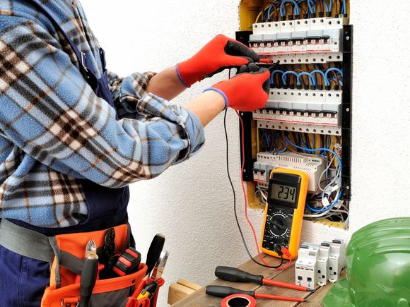 Un electricista está trabajando en una caja eléctrica con un multímetro.