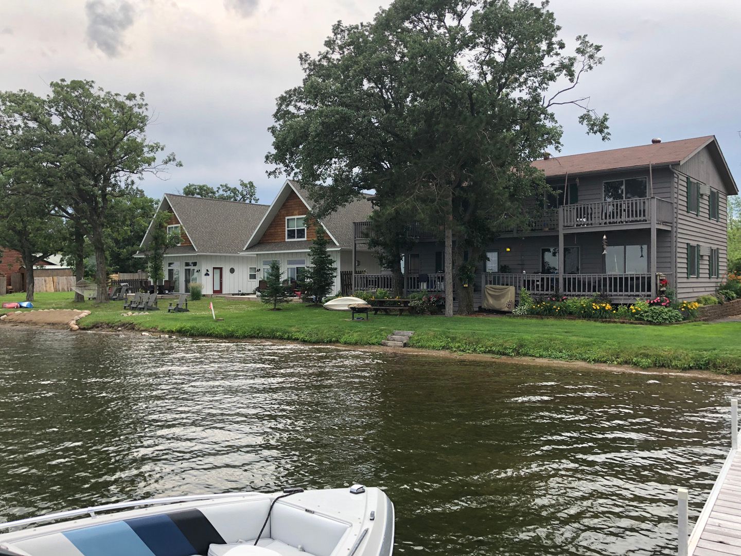 A boat is docked in front of a house on the shore of a lake.
