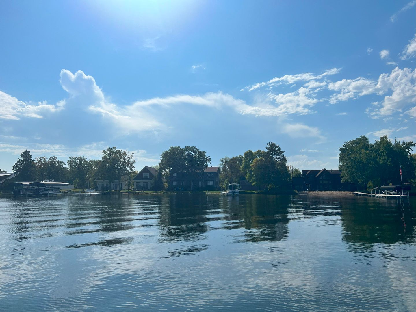 A lake surrounded by trees and houses on a sunny day
