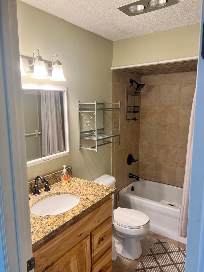 A bathroom with a sink , toilet , tub and mirror