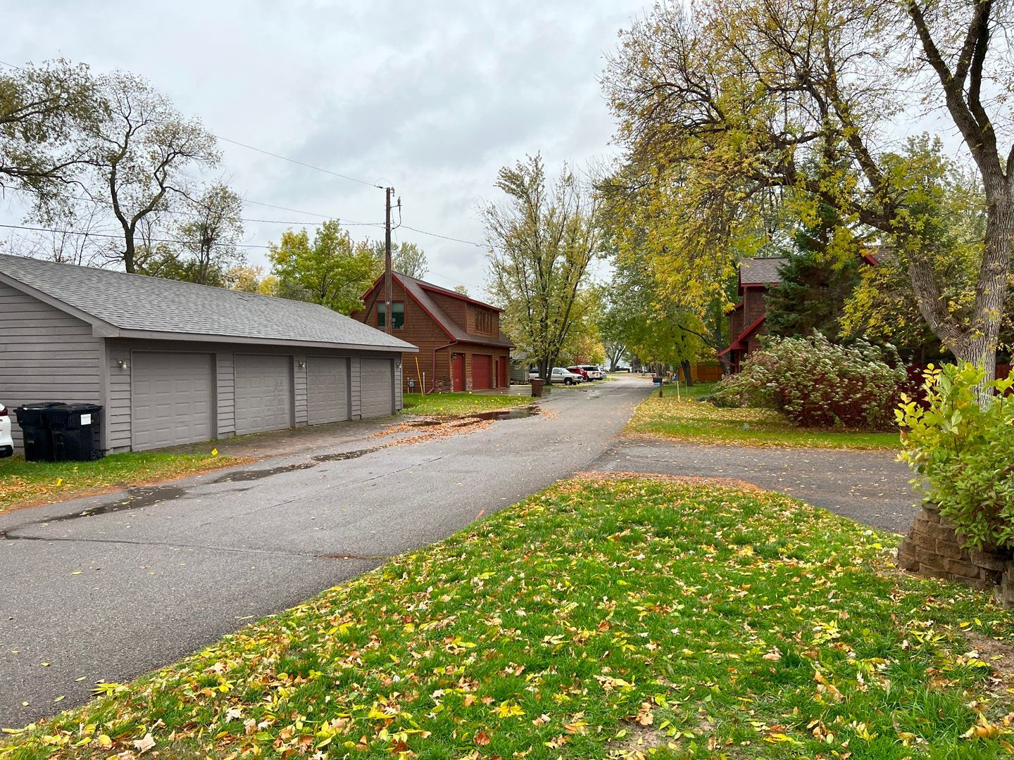 A residential street with a lot of houses and trees on a cloudy day.