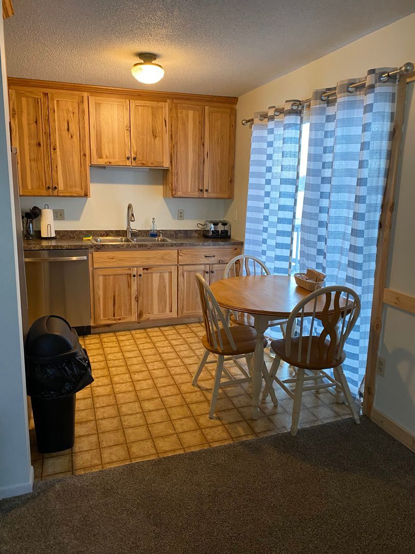A kitchen with wooden cabinets and a table and chairs