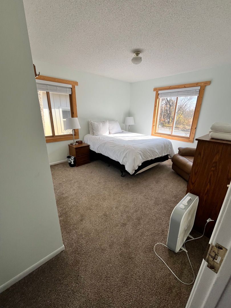 A bedroom with a bed , chair , dresser and window.