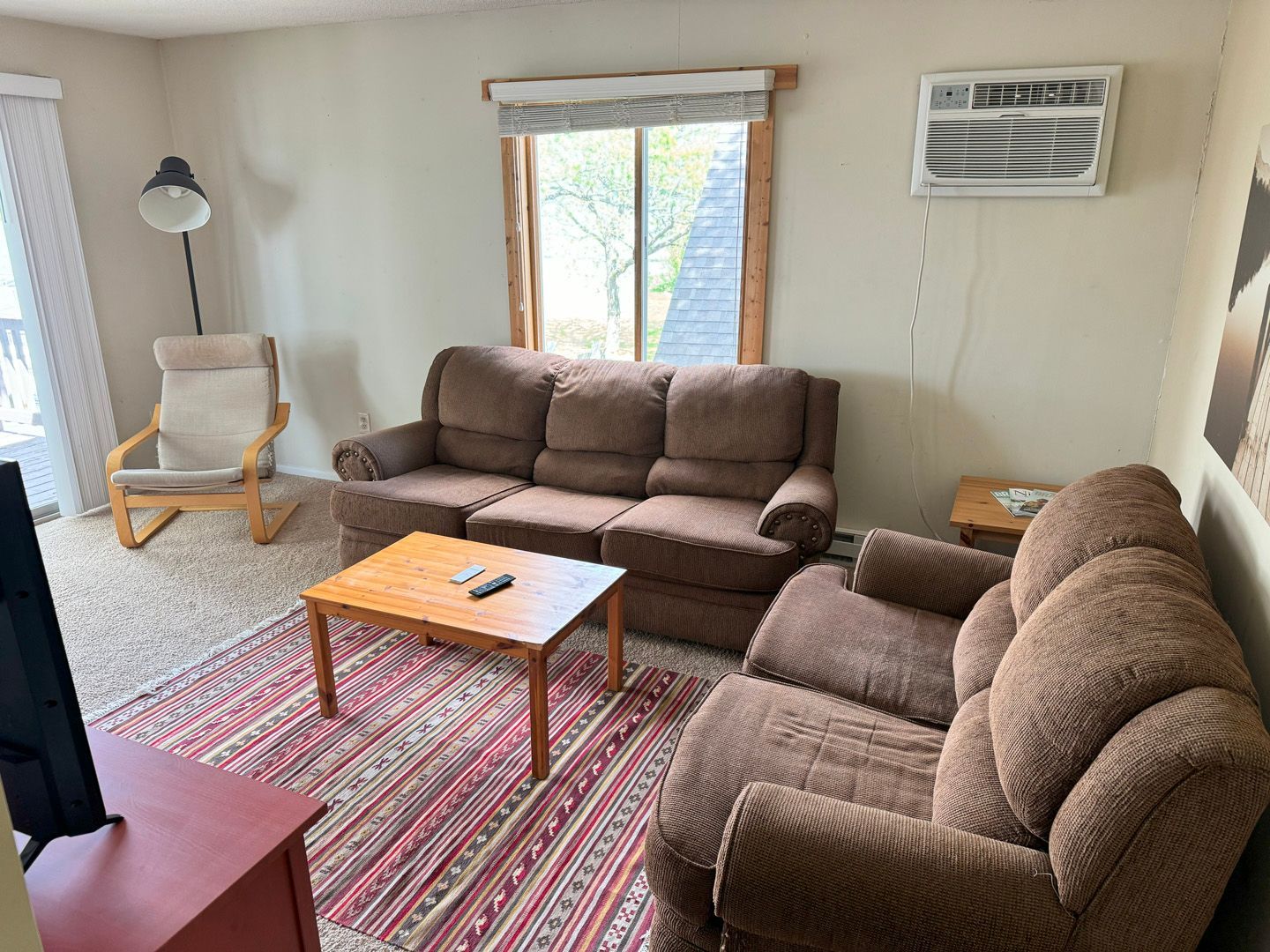 A living room with a couch , chair , table and television.