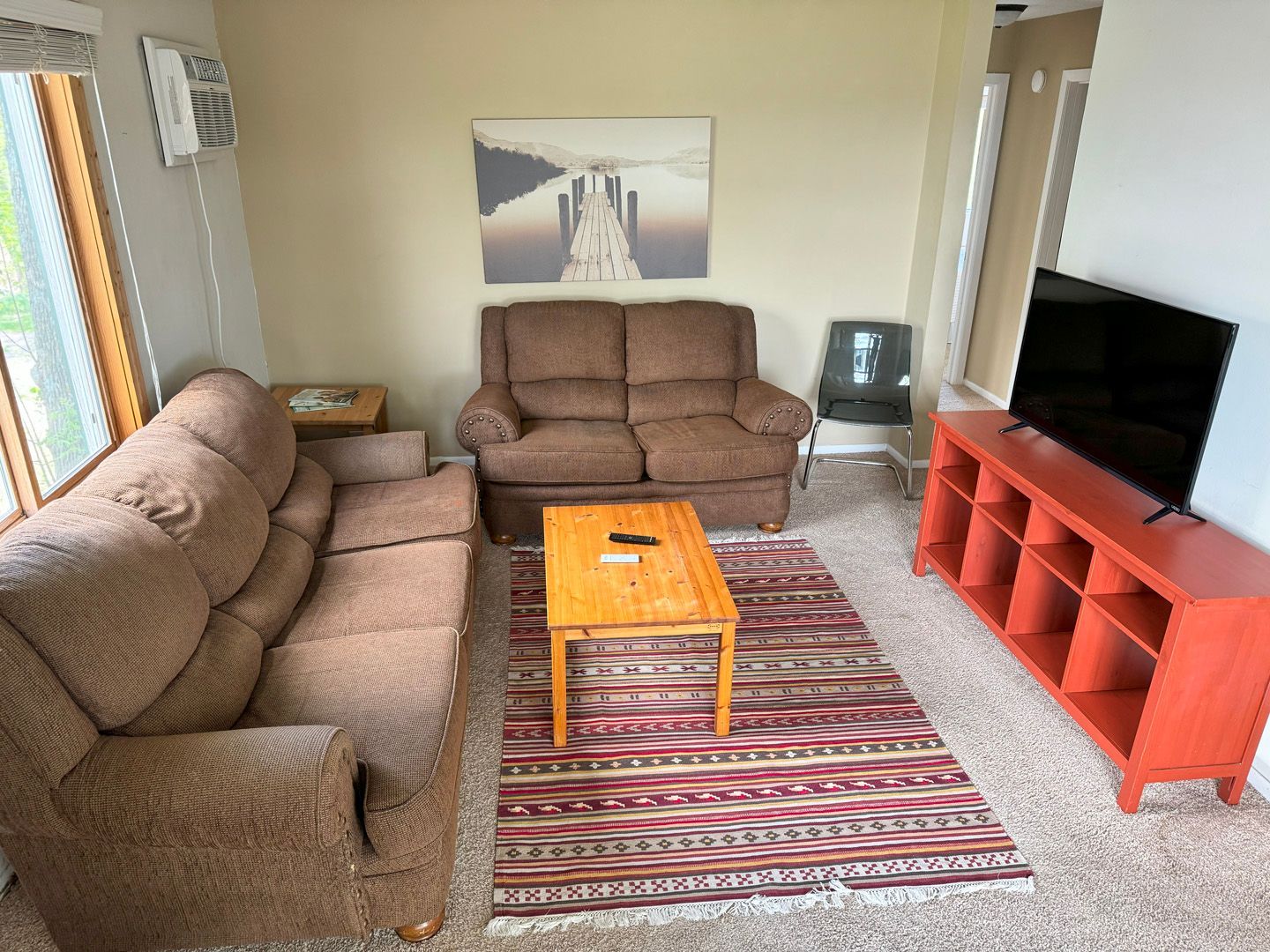 A living room with a couch , chair , coffee table and television.