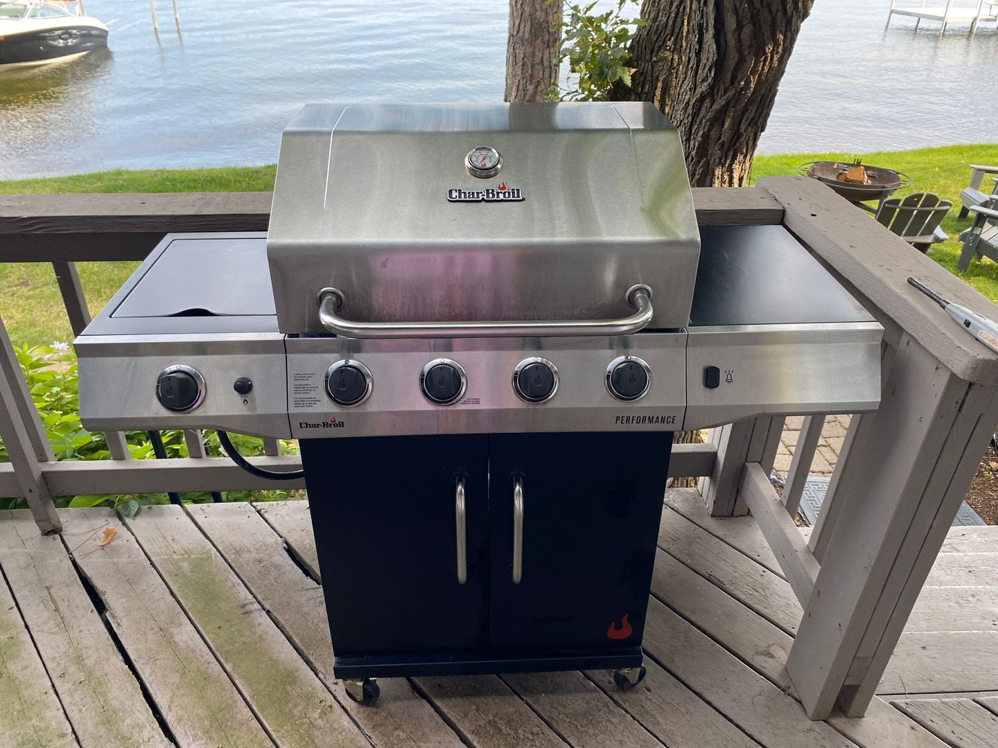 A grill is sitting on a wooden deck next to a body of water.