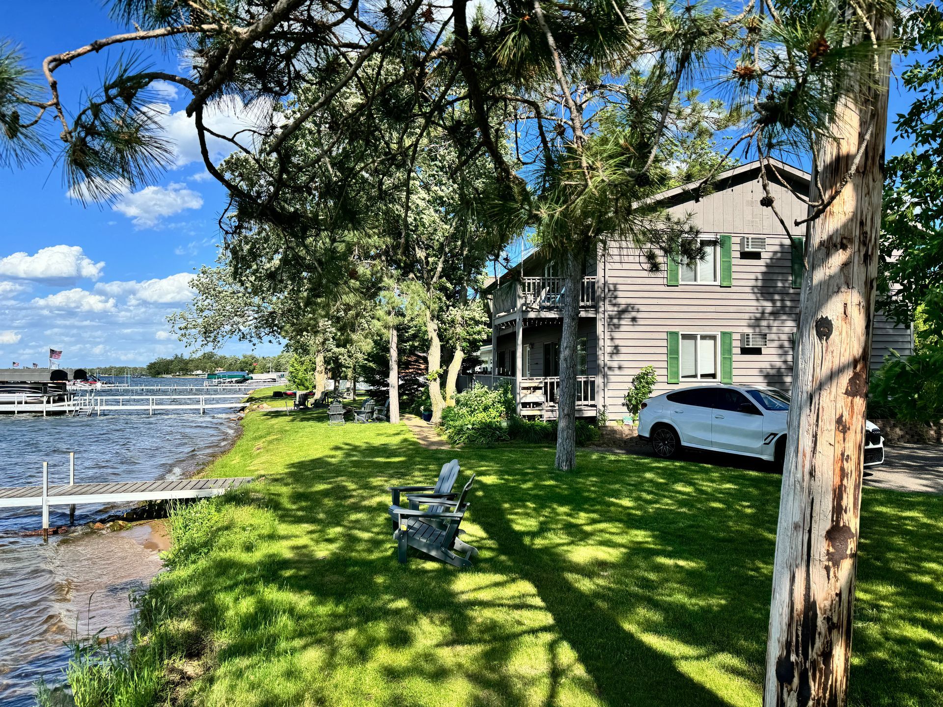 A car is parked in front of a house next to a lake.