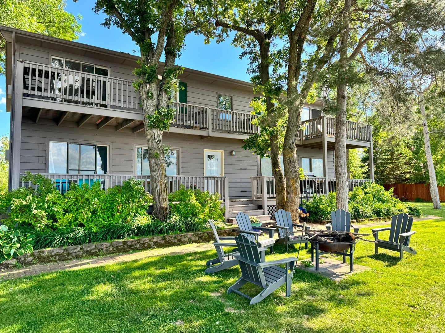 A house with a fire pit and chairs in front of it.