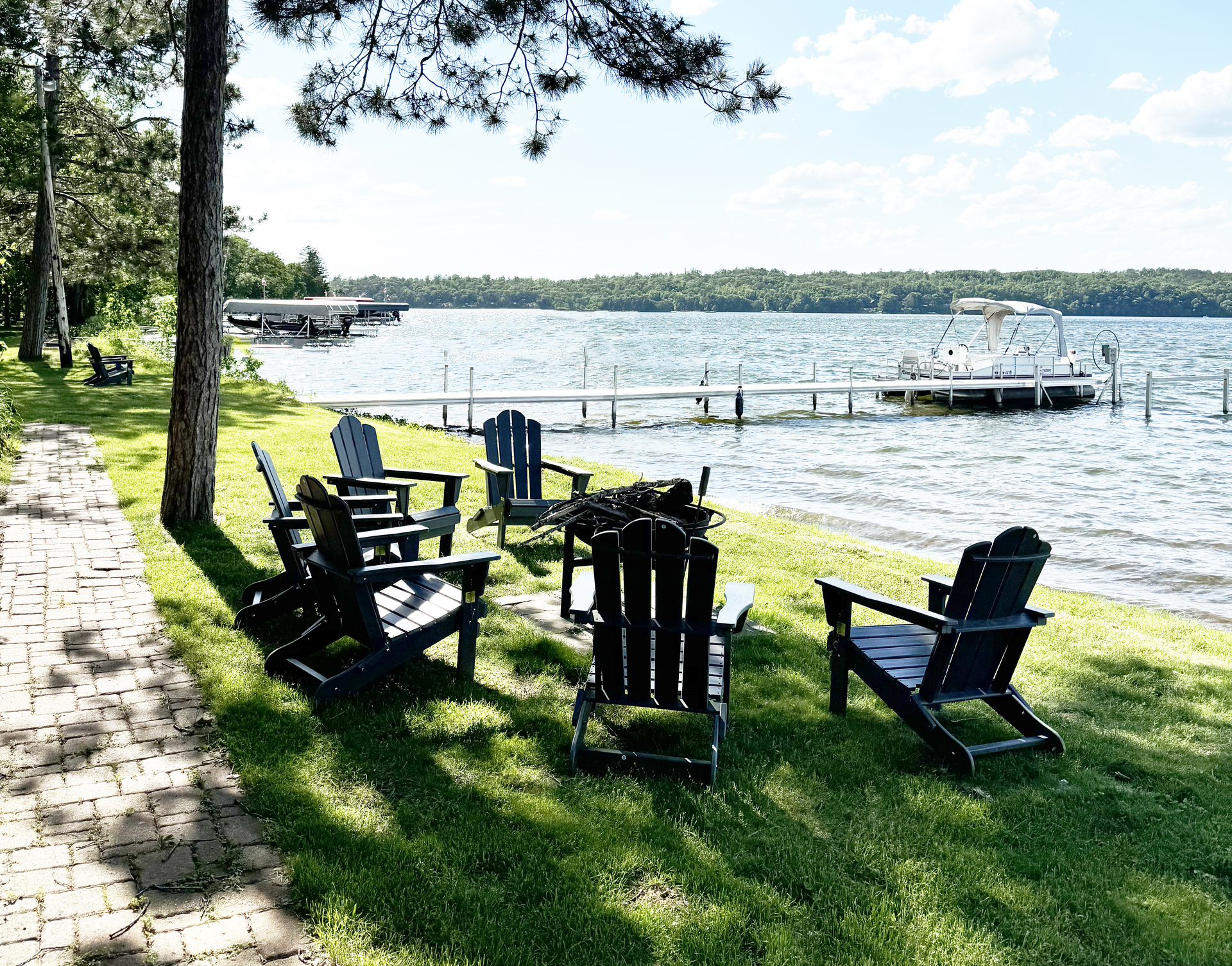 A group of chairs are sitting on the grass near a lake.