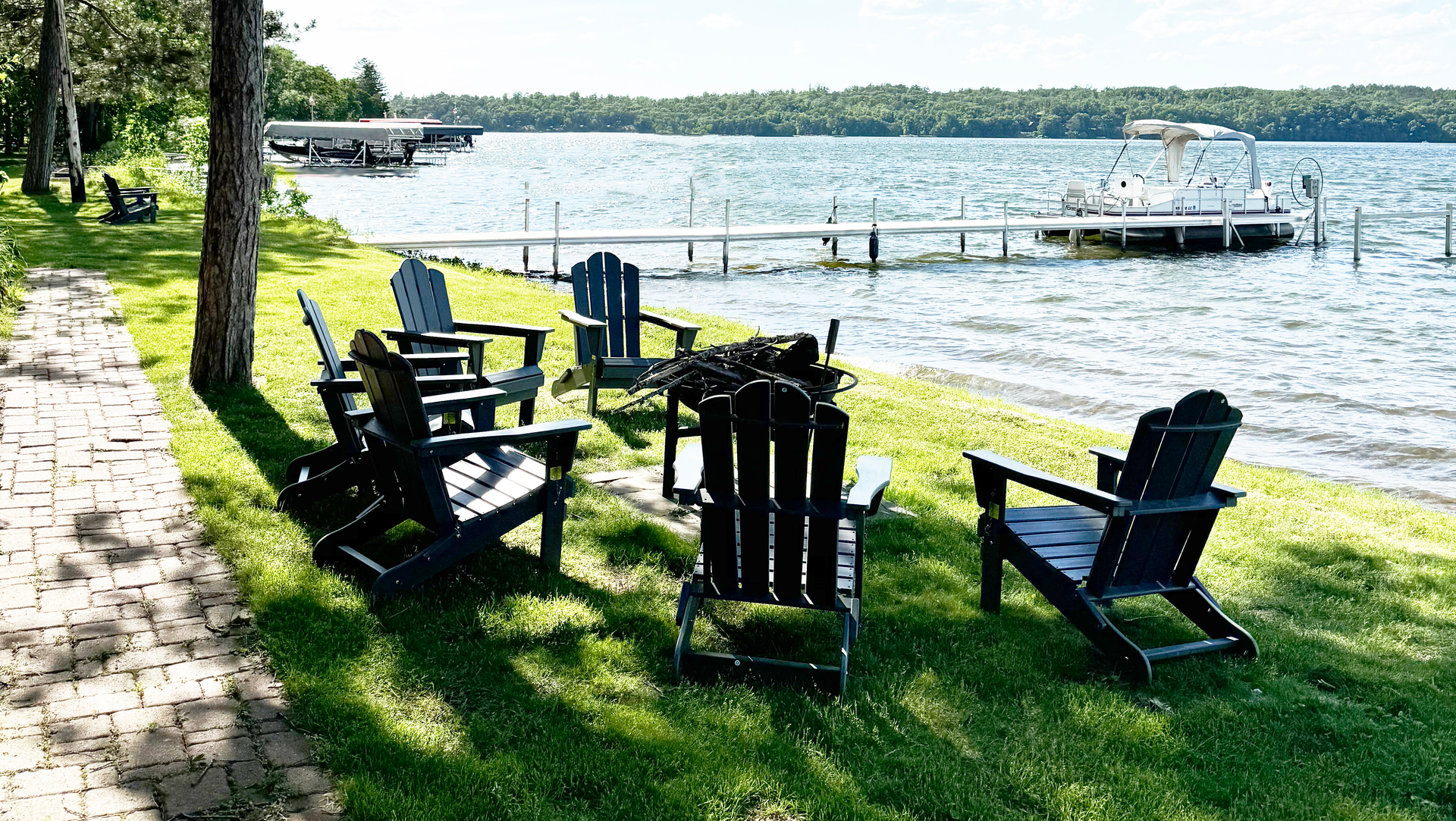 A group of chairs are sitting in the grass near a lake.