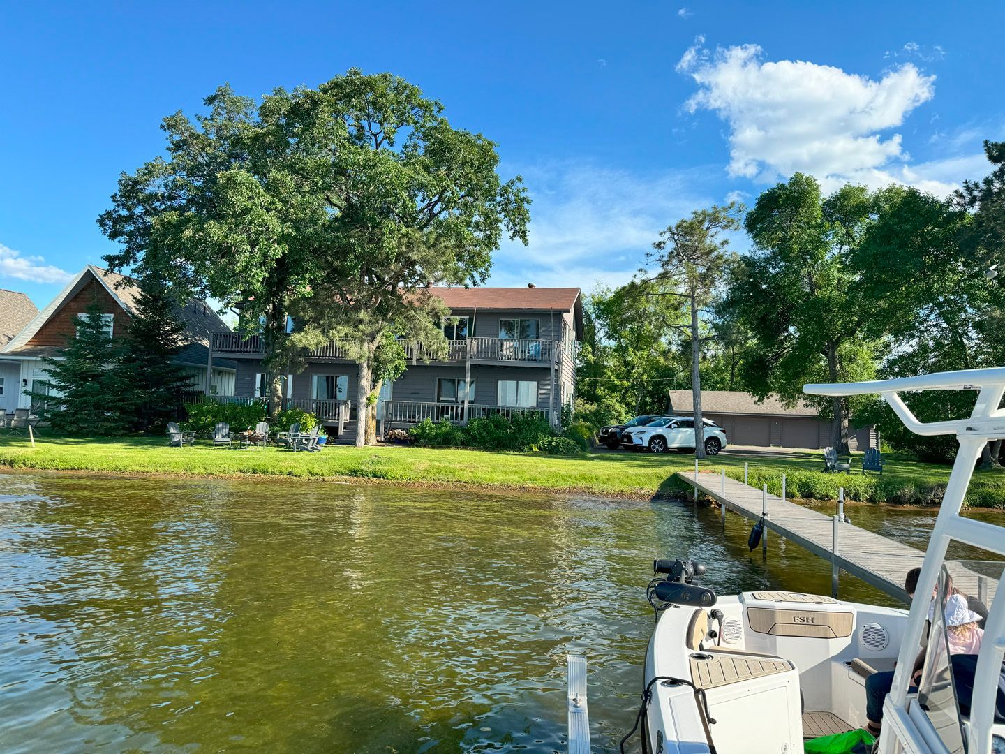 A boat is docked in front of a house on a lake.