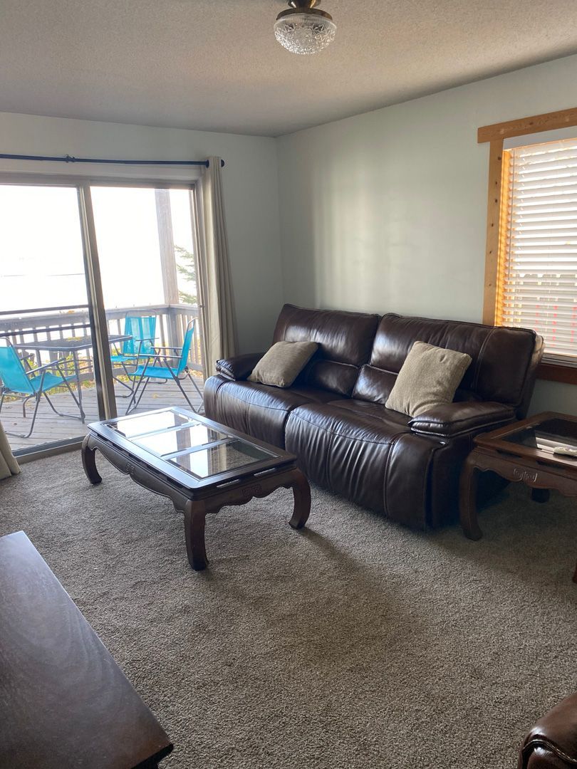 A living room with a couch , table , chairs and sliding glass doors.